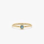 Our Natural Blue Diamond Bezel Ring features a rare and stunning enhanced blue diamond in a modern bezel setting. Handcrafted with solid gold, this dainty ring is perfect for stacking or as an elegant engagement ring.